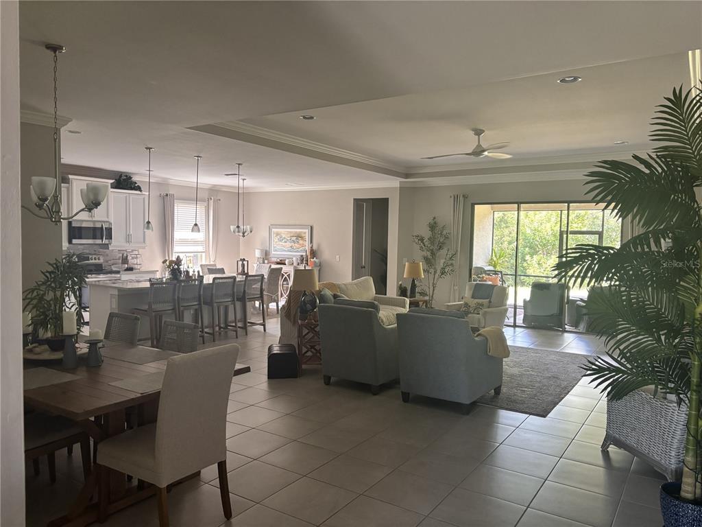 An open-concept living area features a kitchen with an island, dining space, and tiled floors — 288 TOSCAVILLA BOULEVARD, NOKOMIS, FL