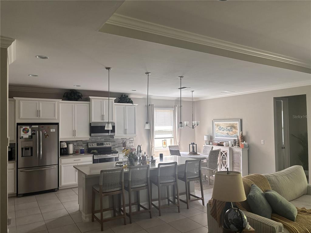 An open-concept kitchen features white cabinetry, a large island with bar seating, and dining area — 288 TOSCAVILLA BOULEVARD, NOKOMIS, FL
