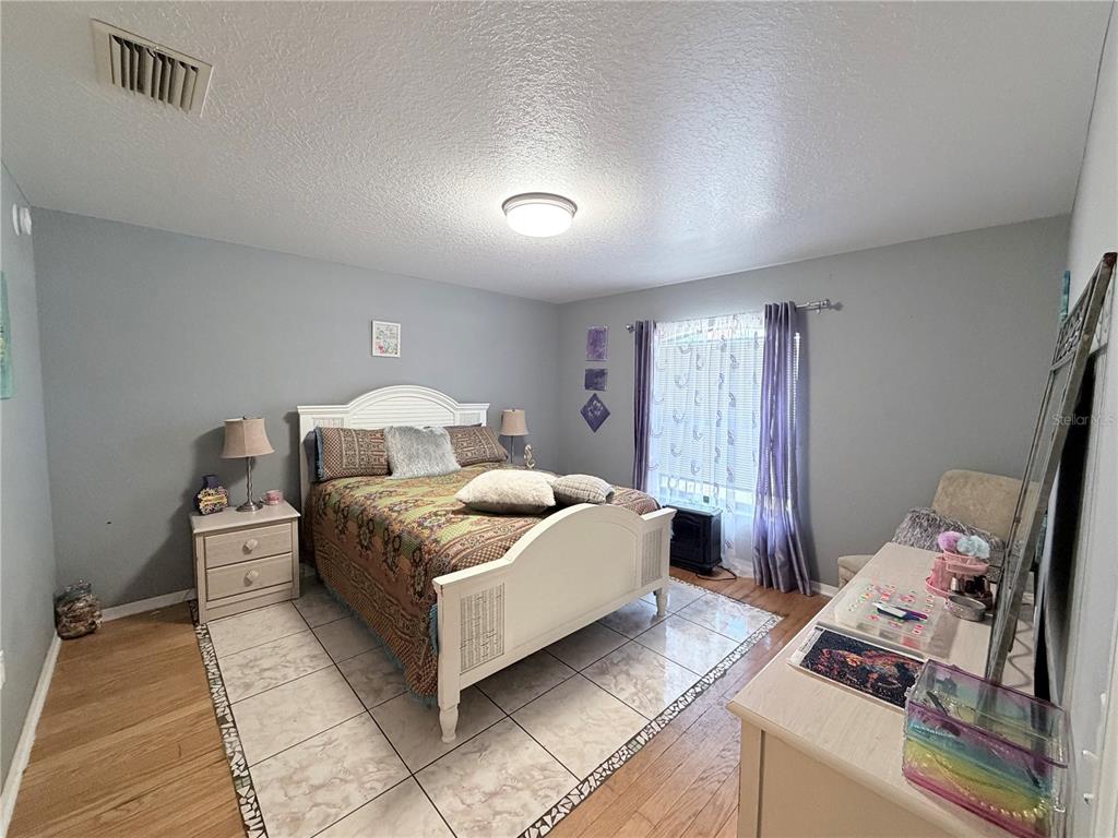 A bedroom features a white bed frame, tile flooring, and a desk against a grey wall — 164 MARION OAKS LANE, OCALA, FL