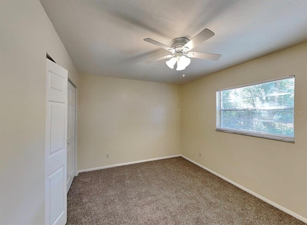 A bedroom with beige walls, brown carpet, a ceiling fan, and a window with blinds — 2102 MONTANA STREET, ORLANDO, FL
