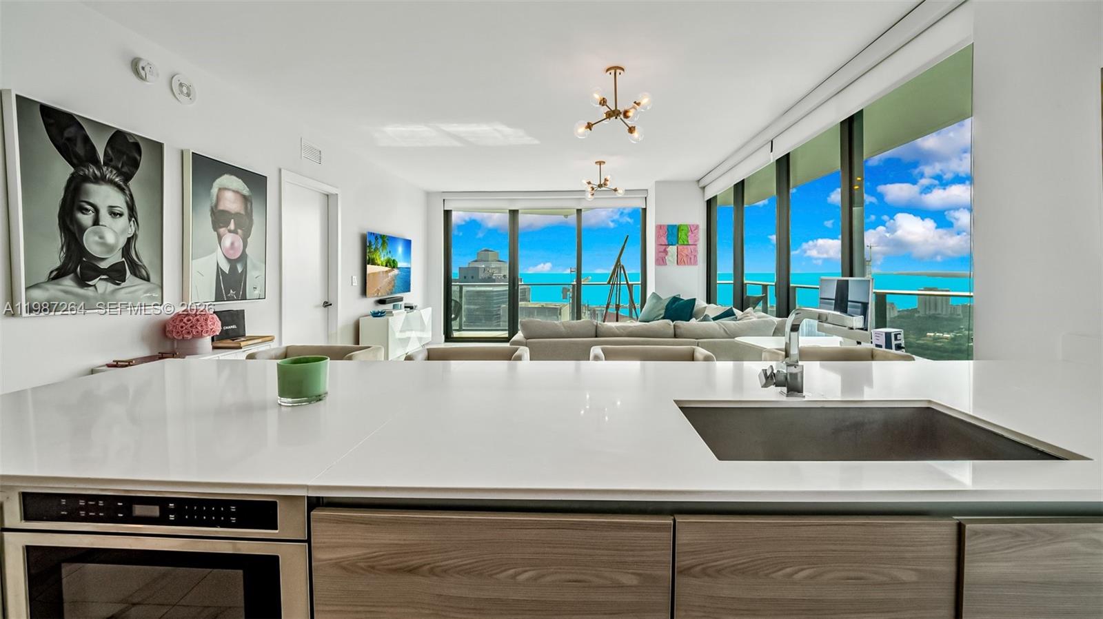A modern kitchen island overlooks a living area with floor-to-ceiling windows and ocean views — 1300 S Miami Ave # 4306, Miami FL 33130, MIAMI, FL