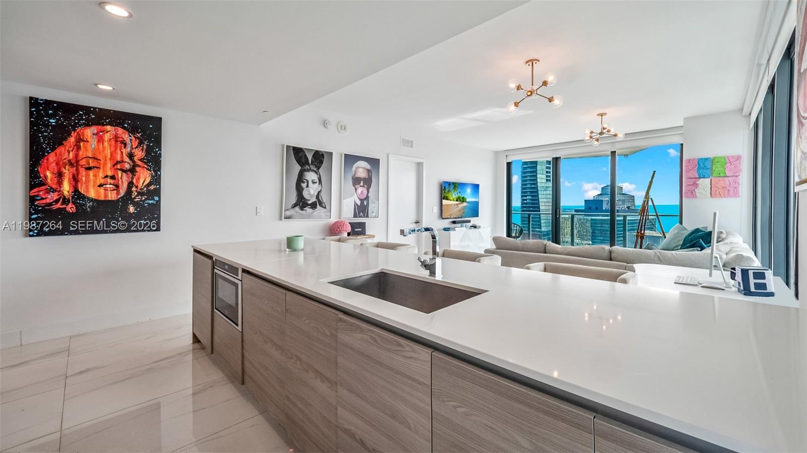 A modern kitchen island with a sink overlooks a living area with ocean views — 1300 S Miami Ave # 4306, Miami FL 33130, MIAMI, FL