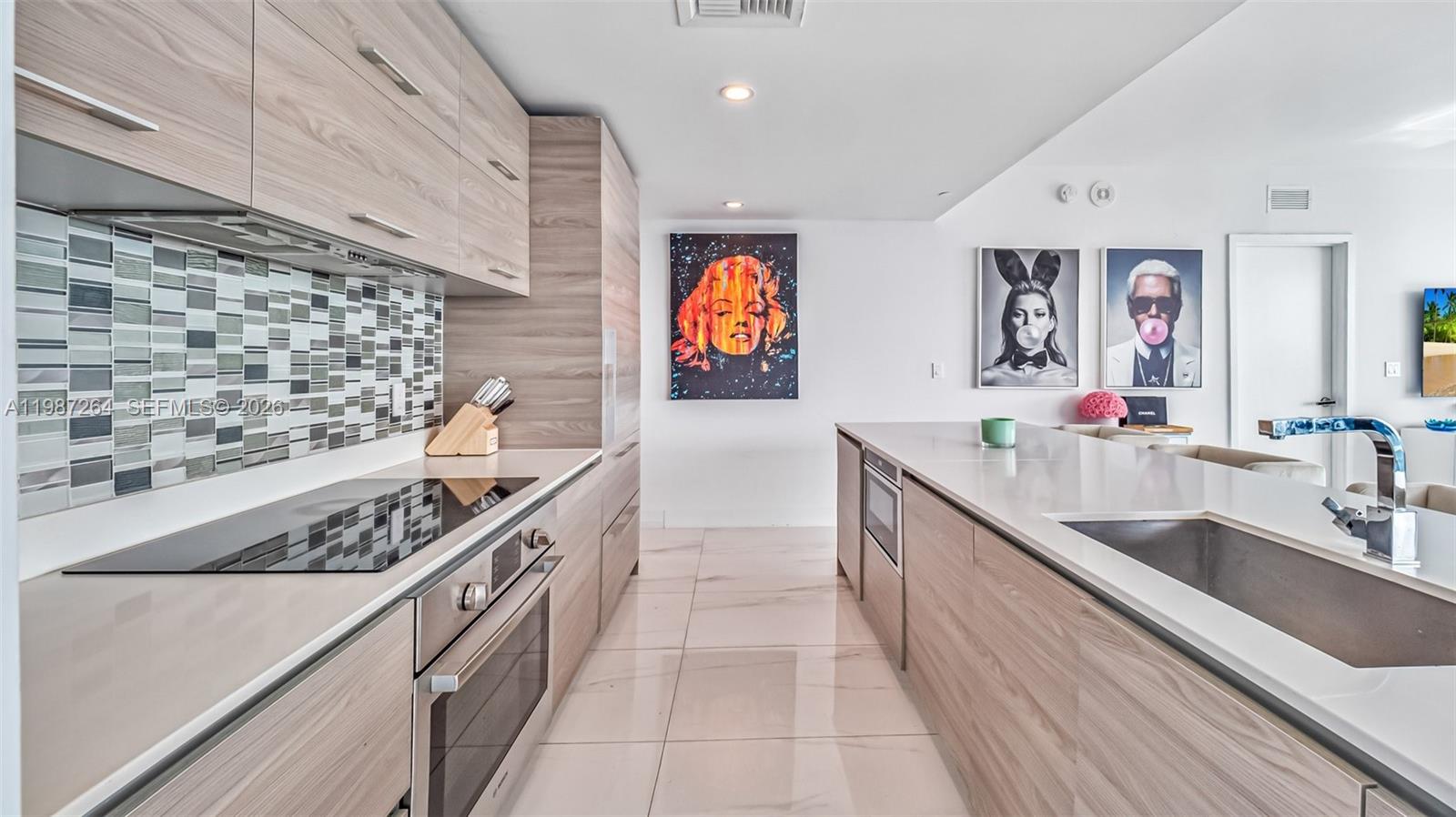 A modern kitchen features light wood cabinetry, a glass cooktop, and a white island — 1300 S Miami Ave # 4306, Miami FL 33130, MIAMI, FL