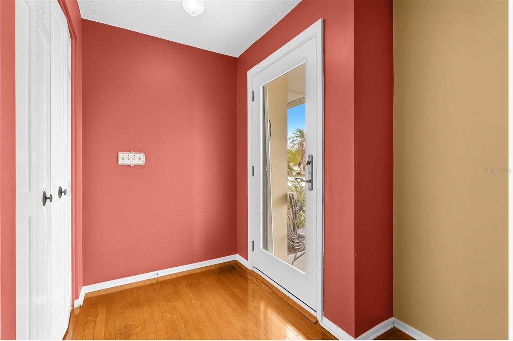 An entryway with hardwood floors, red walls, a white door, and a closet — 1006 DE LEO DRIVE, SARASOTA, FL
