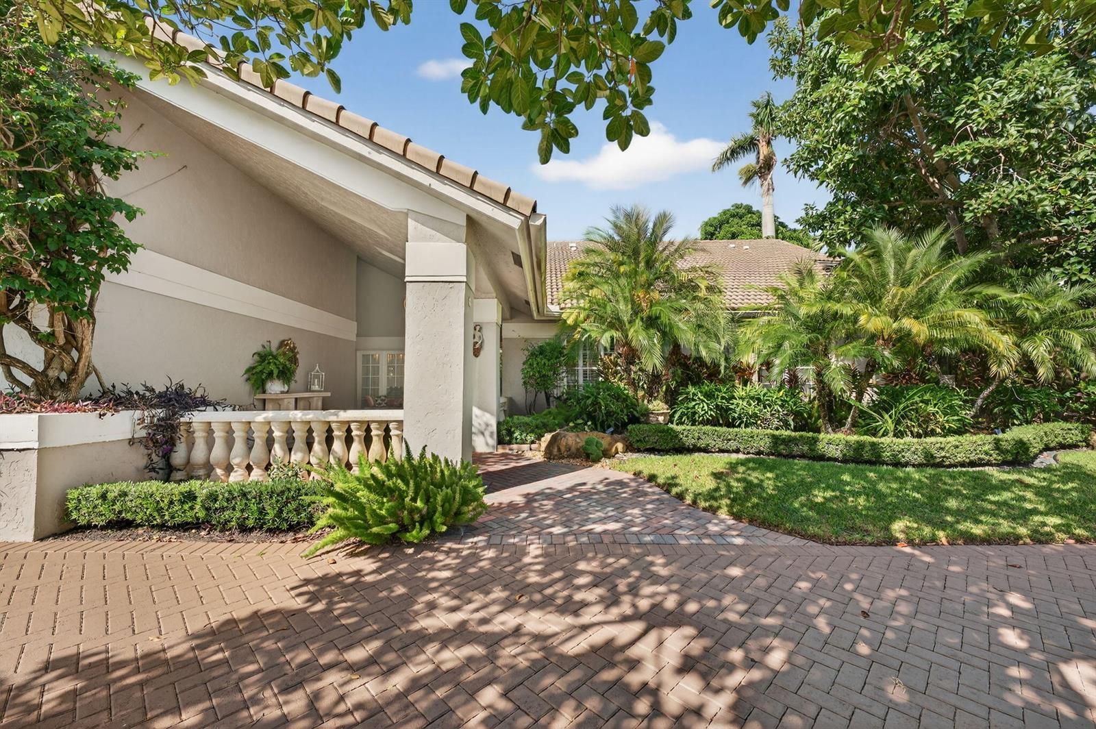 A paved walkway leads to the covered entrance of a house with a stone balustrade — 7205 Mandarin Drive, Boca Raton FL 33433, BOCA RATON, FL