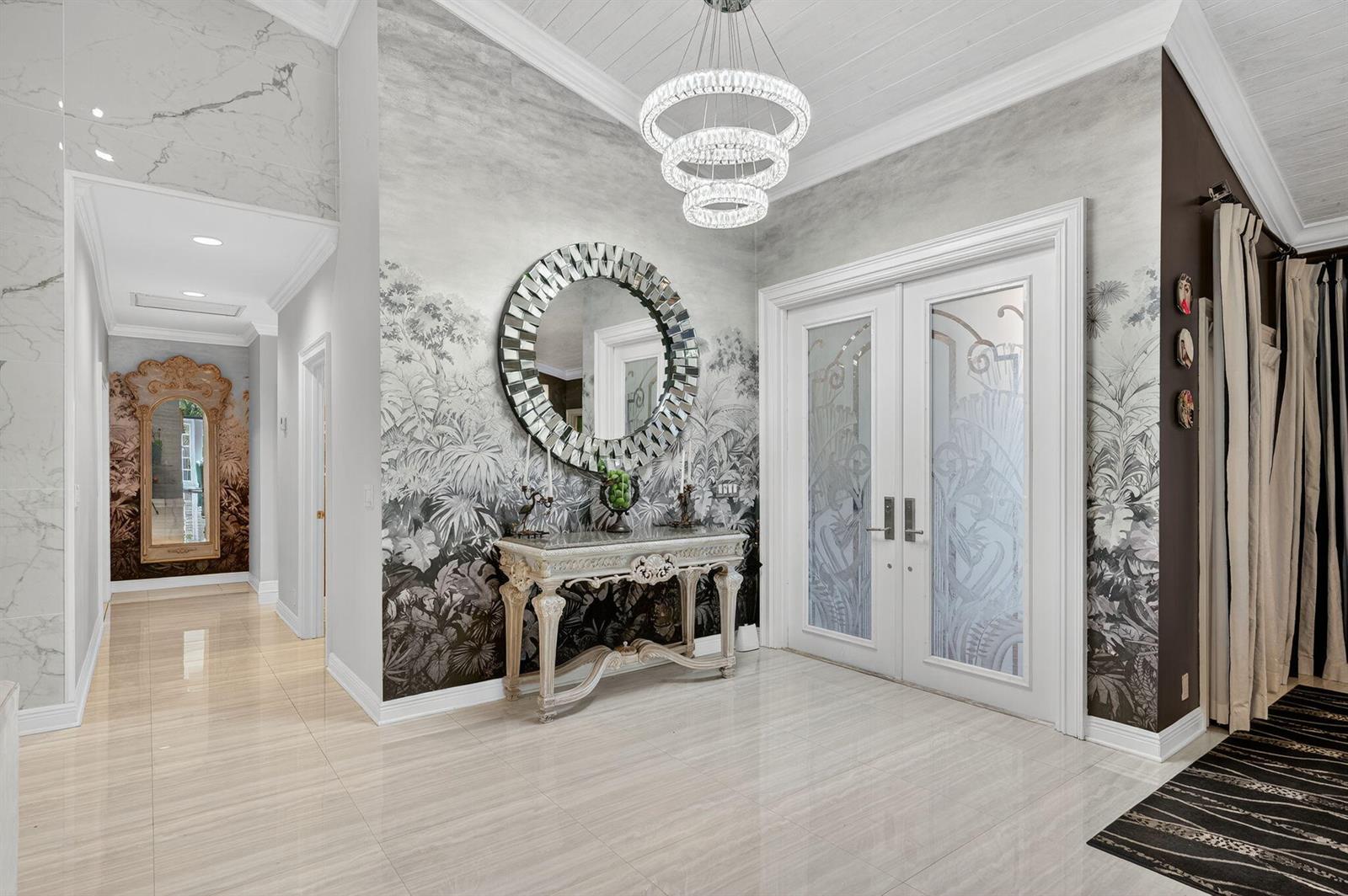 A foyer features a crystal chandelier, a mirrored wall, patterned wallpaper, and a console table — 7205 Mandarin Drive, Boca Raton FL 33433, BOCA RATON, FL