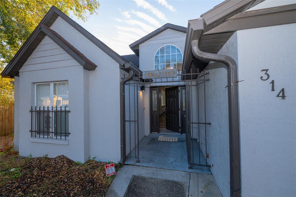 The exterior of a house features a gated entryway, a front door, and house number 314 — 314 ALMA STREET, KISSIMMEE, FL