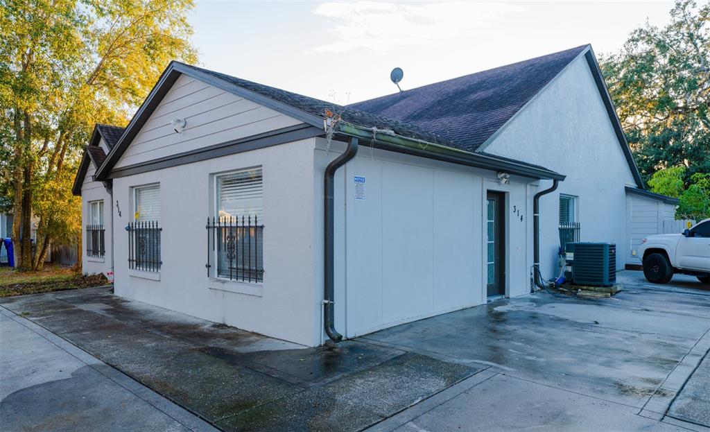 A white single-story building with a dark shingled roof and a concrete driveway — 314 ALMA STREET, KISSIMMEE, FL