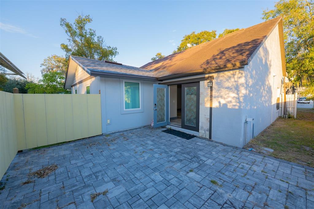 A paved patio sits outside a house with a light blue wall and glass doors — 314 ALMA STREET, KISSIMMEE, FL