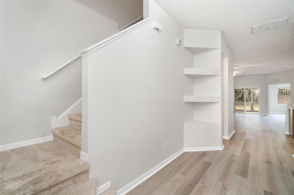 A staircase with carpeted steps sits beside a wall featuring built-in corner shelves — 9317 STONE RIVER PLACE, RIVERVIEW, FL