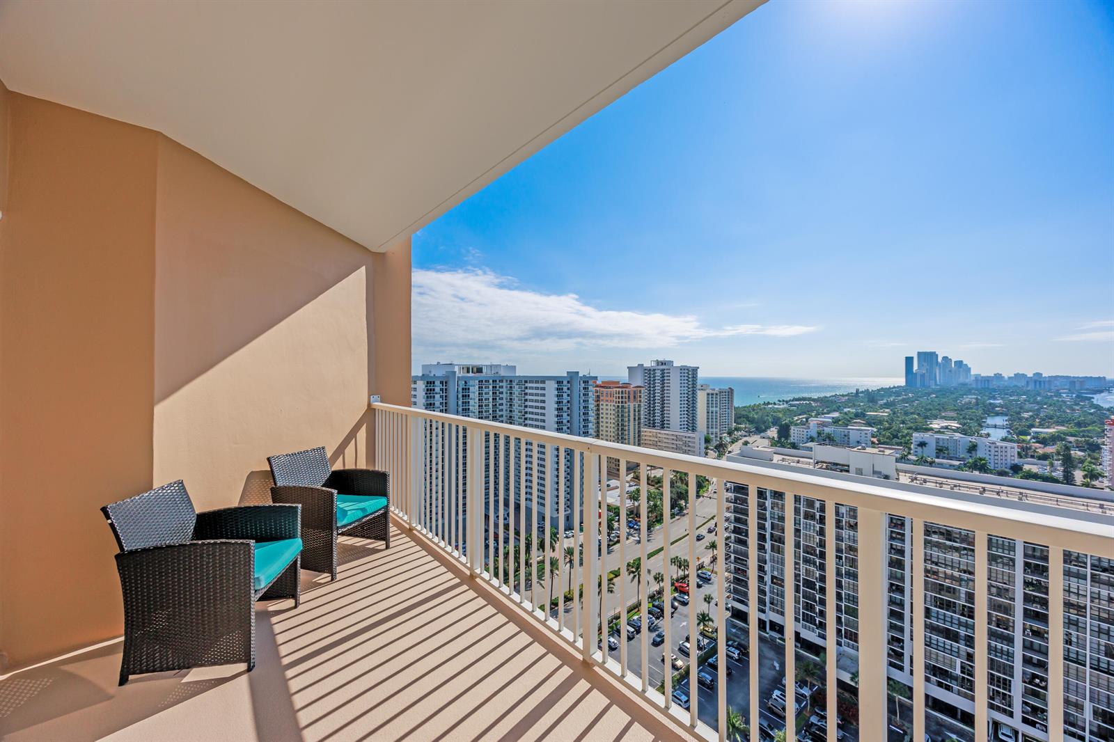 A high-rise balcony with a white railing overlooks a city and waterway under clear skies — 1985 S Ocean Drive, Hallandale Beach FL 33009, HALLANDALE BEACH, FL