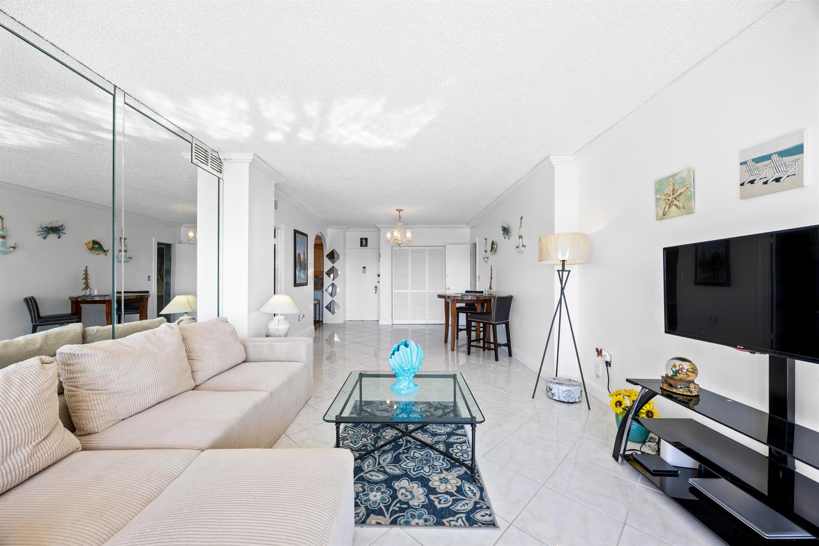 A living room features a beige sectional sofa, glass coffee table, and balcony with city views — 1985 S Ocean Drive, Hallandale Beach FL 33009, HALLANDALE BEACH, FL