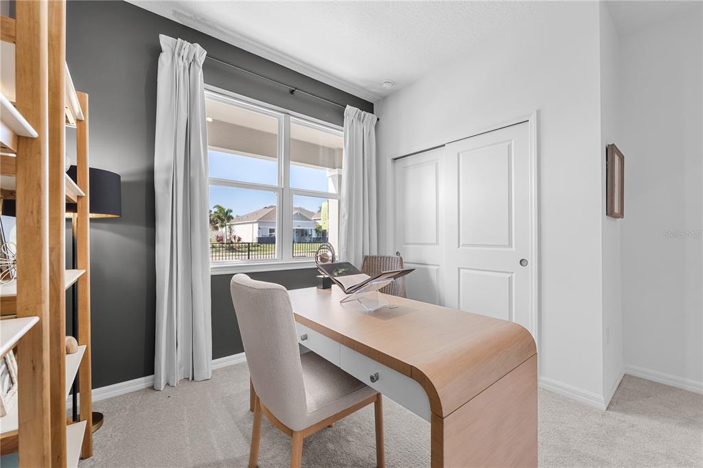 A home office features a wooden desk, a chair, a window, and a closet — 1813 SHADOW BOX BEND, ST CLOUD, FL