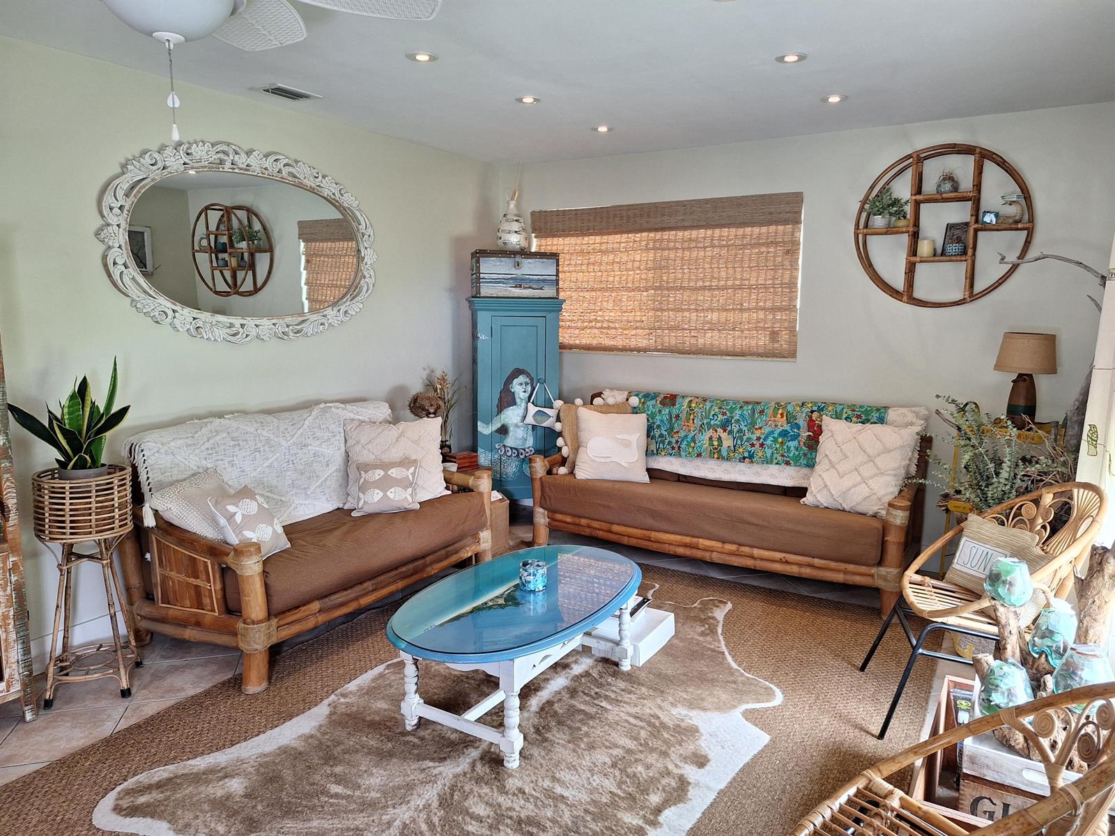A living room features bamboo furniture, a cowhide rug, and a mermaid-painted cabinet — 217 SE 2nd Avenue, Boynton Beach FL 33435, BOYNTON BEACH, FL