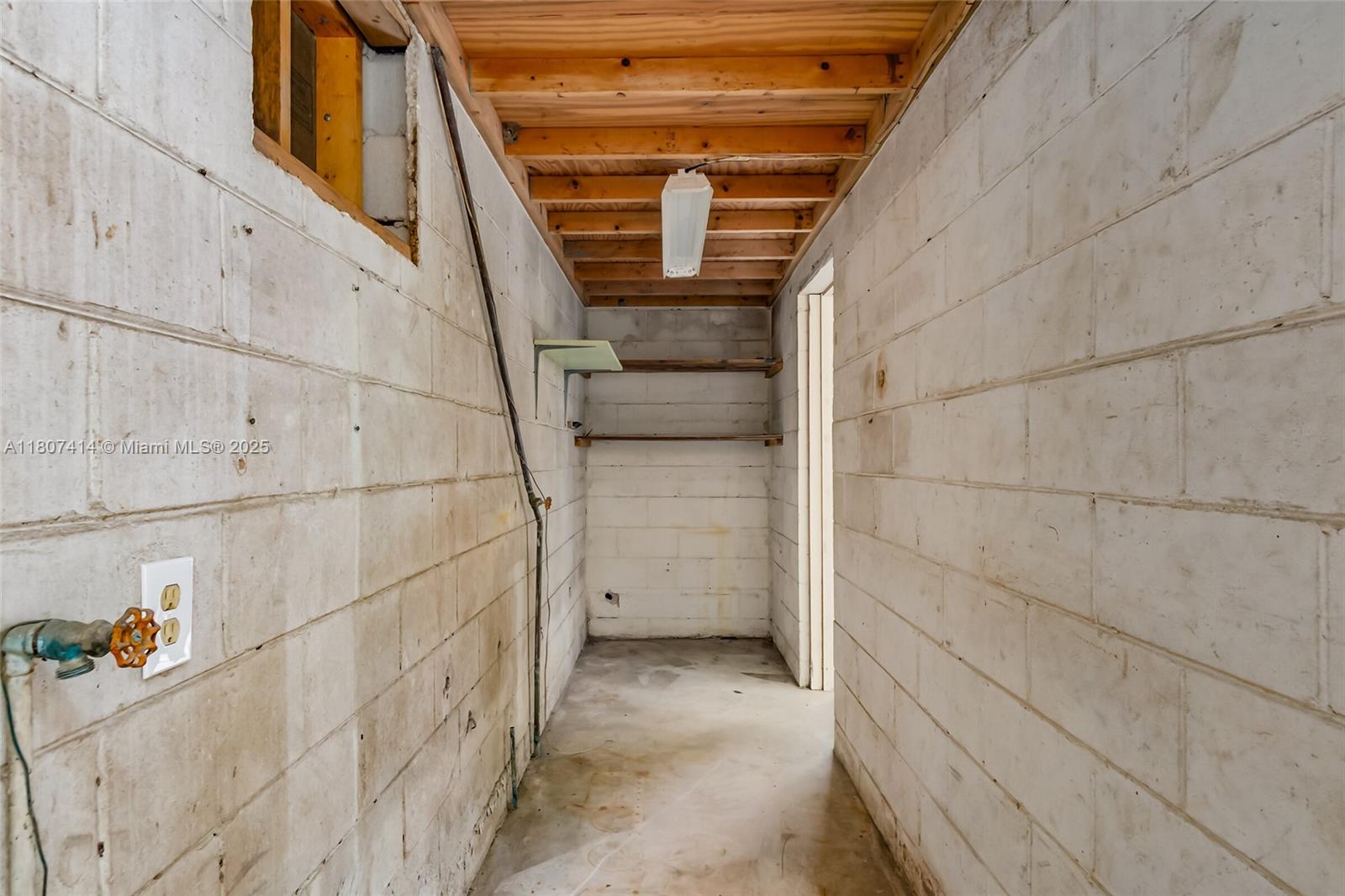 A utility room features unfinished concrete block walls, exposed wooden ceiling joists, and a water spigot — 2826 2830 HESTER AVE, Palm Bay FL 32909, PALM BAY, FL