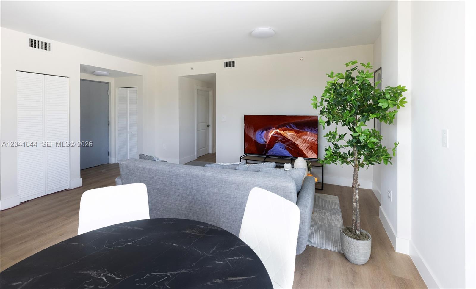 A living room features a grey sofa, a television, and a dining table with chairs — 37XX NW 23 Ave # 16, Miami FL 33142, MIAMI, FL