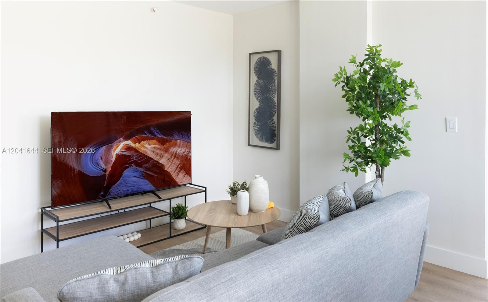 A living room features a grey sofa, a wooden coffee table, and a television stand — 37XX NW 23 Ave # 16, Miami FL 33142, MIAMI, FL