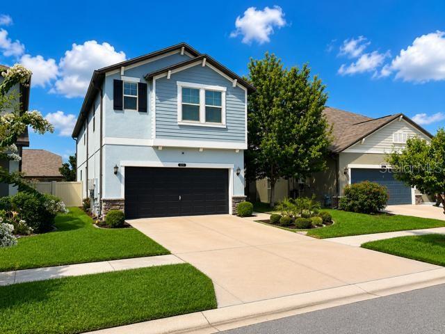 A two-story blue house with a two-car garage and a concrete driveway — 8913 FLOURISH DRIVE, LAND O LAKES, FL