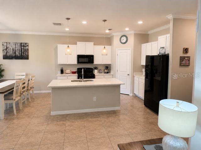 A kitchen features white cabinets, a central island, stainless steel appliances, and tile flooring — 8913 FLOURISH DRIVE, LAND O LAKES, FL