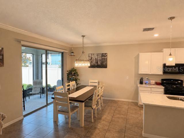 A dining area with a wooden table and chairs sits next to a kitchen island — 8913 FLOURISH DRIVE, LAND O LAKES, FL