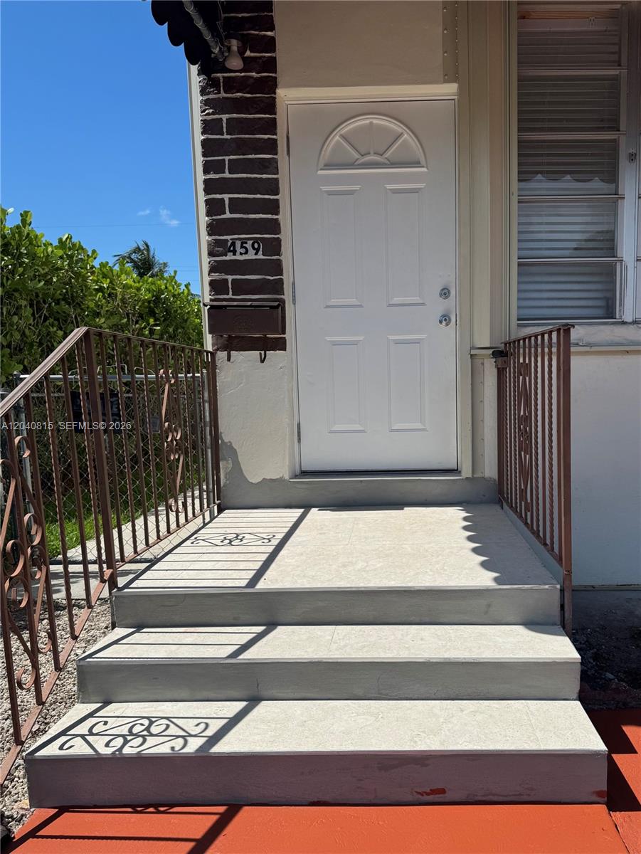 A white front door with a small arched window sits above concrete steps with railings — 459 SE 3rd St, Hialeah FL 33010, HIALEAH, FL