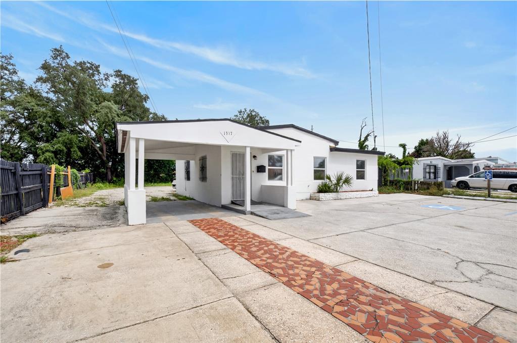 A white single-story house features a carport, a paved parking area, and a tiled walkway — 1317 N PINE HILLS ROAD, ORLANDO, FL