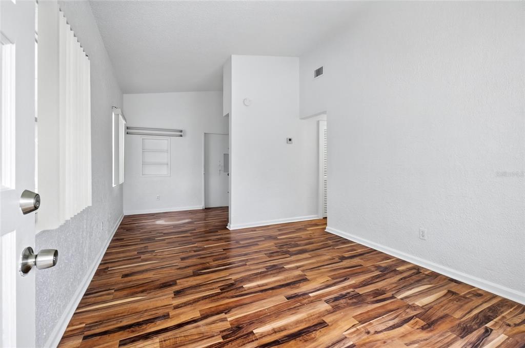 An empty room with white walls, high ceilings, and dark wood-look laminate flooring — 1317 N PINE HILLS ROAD, ORLANDO, FL