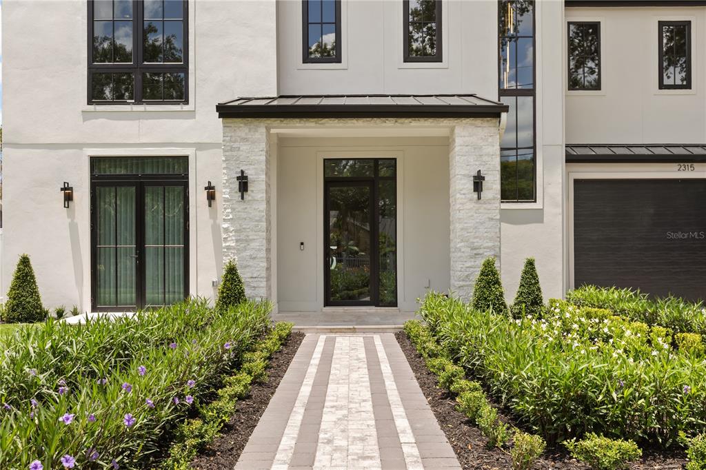 A modern white house exterior features a stone-accented entryway, a paved walkway, and landscaping — 2315 WEBER STREET, ORLANDO, FL