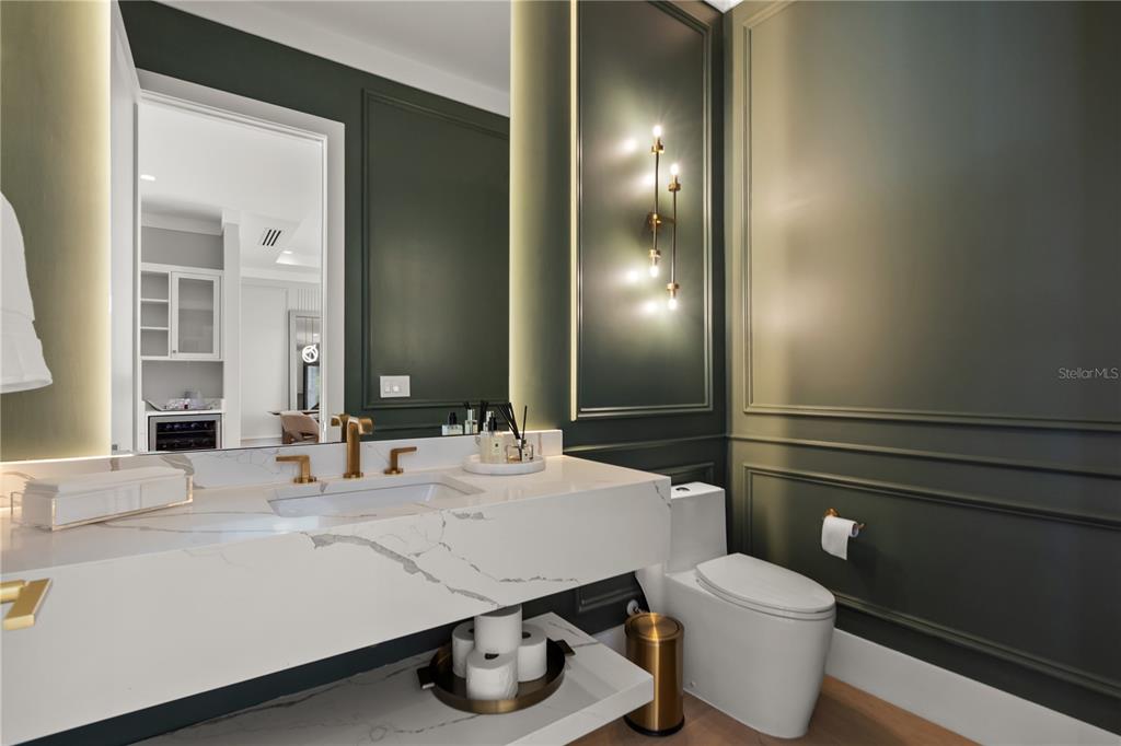 A modern bathroom features a marble vanity, dark green paneled walls, and gold light fixtures — 2315 WEBER STREET, ORLANDO, FL