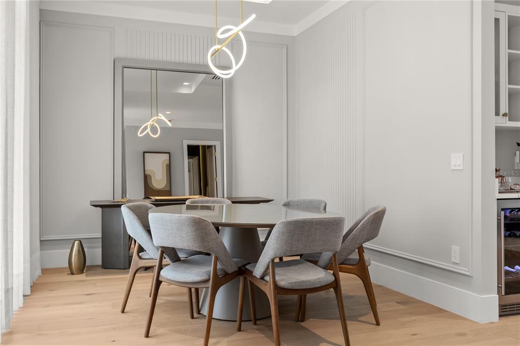 A dining room features a round table, four upholstered chairs, a large mirror, and modern lighting — 2315 WEBER STREET, ORLANDO, FL