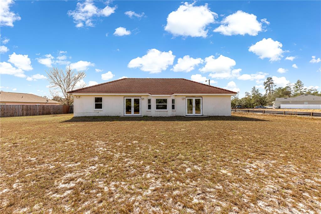 A rear view of a single-story house with a tiled roof and a large yard — 17179 SW 41ST CIRCLE, OCALA, FL