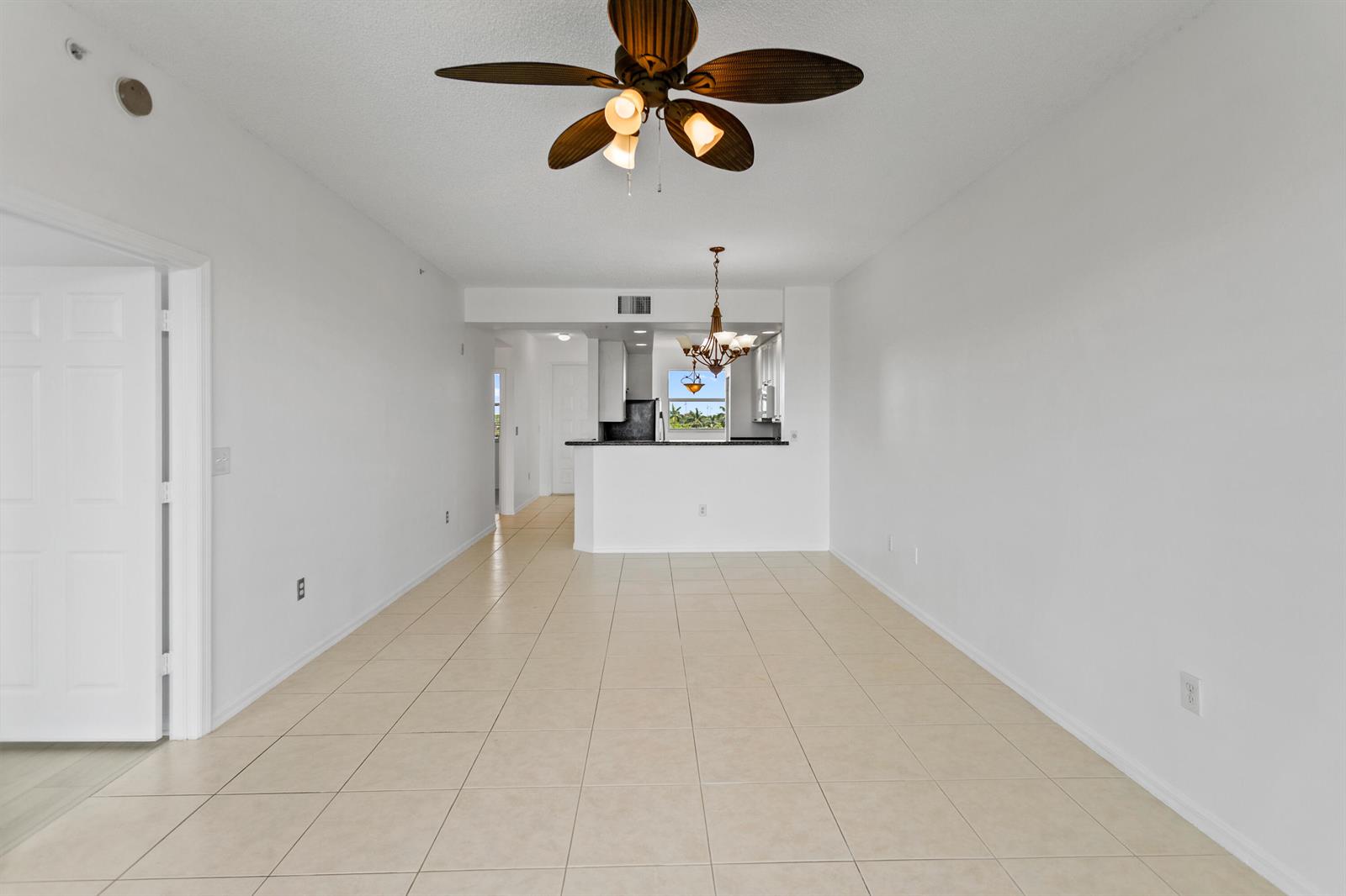 An empty living and dining area with white walls, tile floors, and a ceiling fan — 27 Royal Palm Way # 503, Boca Raton FL 33432, BOCA RATON, FL