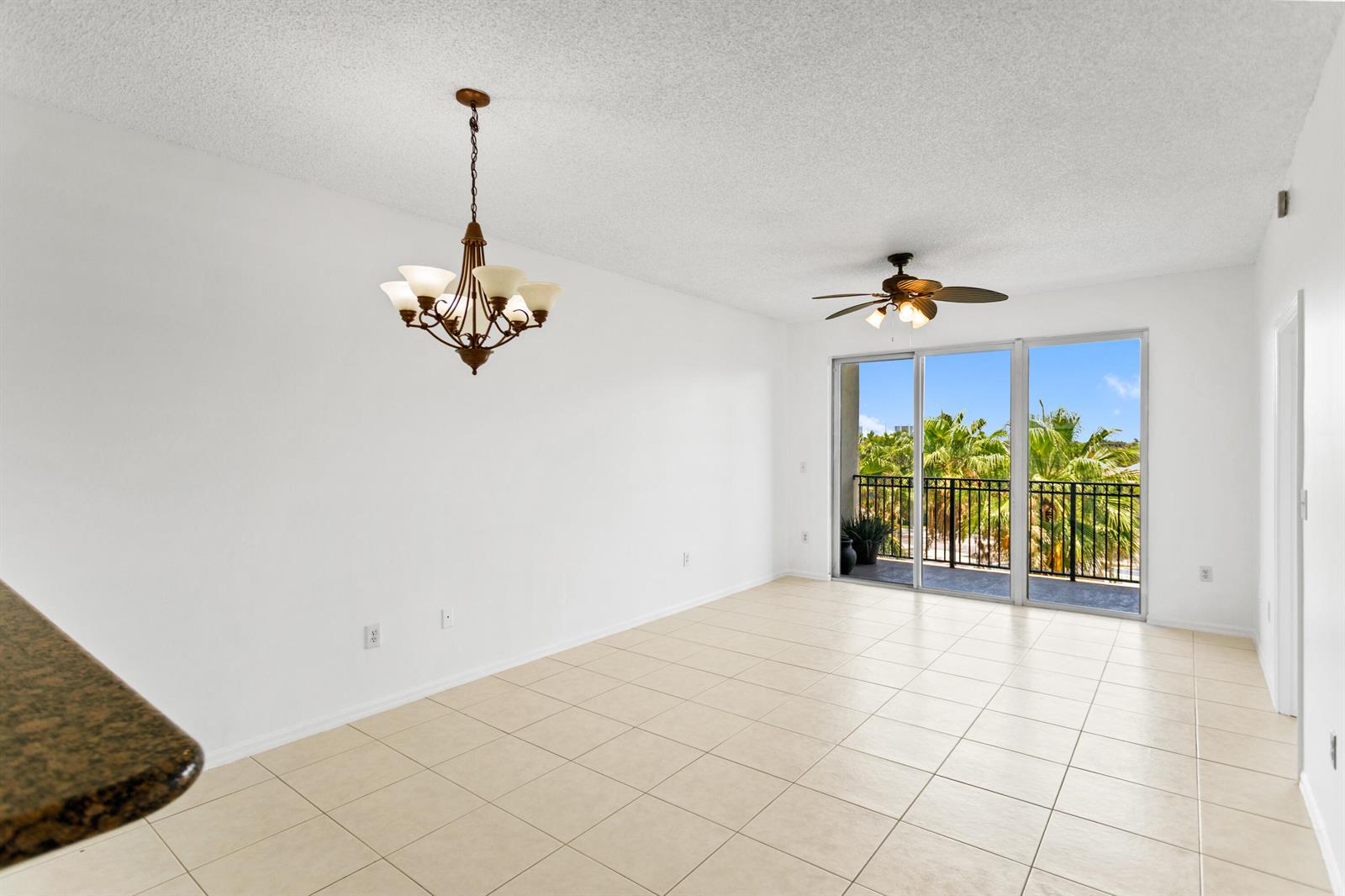 An empty room with tile flooring, a ceiling fan, a chandelier, and sliding glass doors — 27 Royal Palm Way # 503, Boca Raton FL 33432, BOCA RATON, FL