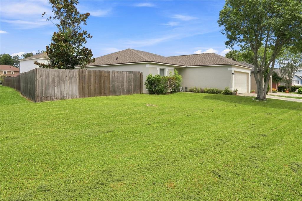 A single-story house with a beige exterior, a tan roof, and a wooden privacy fence — 4243 MENDENWOOD LANE, ORLANDO, FL