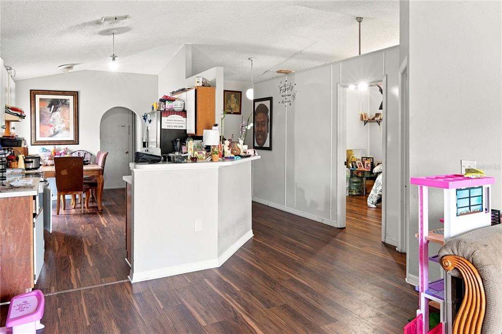A kitchen with a breakfast bar opens into a dining area and a hallway — 4243 MENDENWOOD LANE, ORLANDO, FL