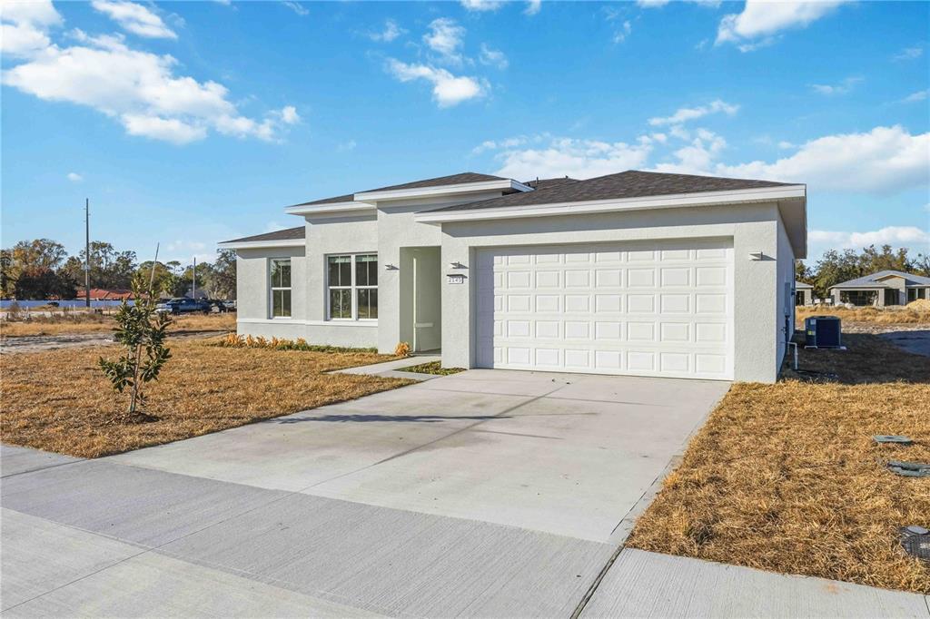 A single-story house with a white stucco exterior, a two-car garage, and a concrete driveway — 2145 RIVER HAWK LOOP, WINTER HAVEN, FL