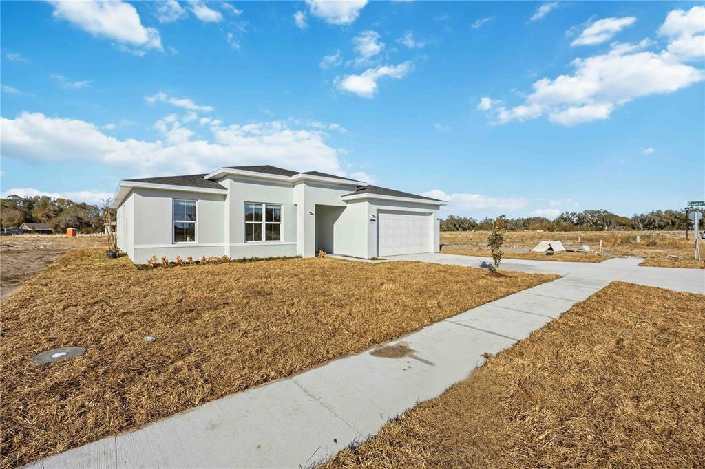 A single-story, light-colored stucco house with a two-car garage and a concrete walkway — 2145 RIVER HAWK LOOP, WINTER HAVEN, FL