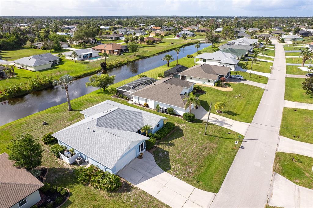 An aerial view shows a suburban neighborhood with single-family homes, a canal, and streets — 15 BUNKER PLACE, ROTONDA WEST, FL