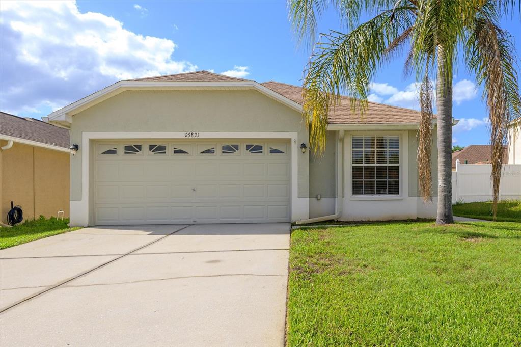 A single-story house with a two-car garage, a palm tree, and a concrete driveway — 25831 SYME COURT, LAND O LAKES, FL