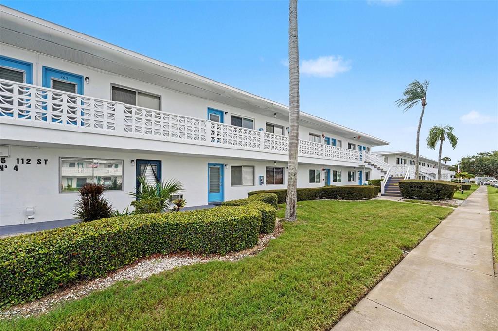 A two-story apartment building with a white facade, blue doors, and decorative concrete railings — 8555 112TH STREET N UNIT 204, SEMINOLE, FL