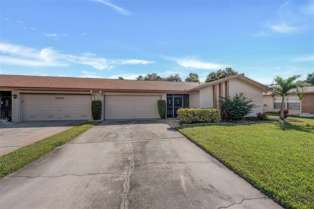 A single-story house with two garage doors and a concrete driveway under a blue sky — 5584 BURING COURT, FORT MYERS, FL