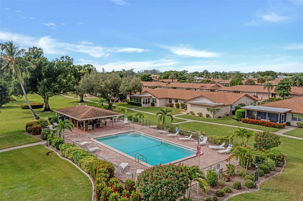 An aerial view shows a rectangular swimming pool, a covered patio, and surrounding residential buildings — 5584 BURING COURT, FORT MYERS, FL