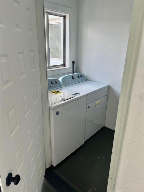 A small laundry room contains a white top-loading washing machine and a matching dryer — 146 BOUNDARY BOULEVARD UNIT B 102, ROTONDA WEST, FL