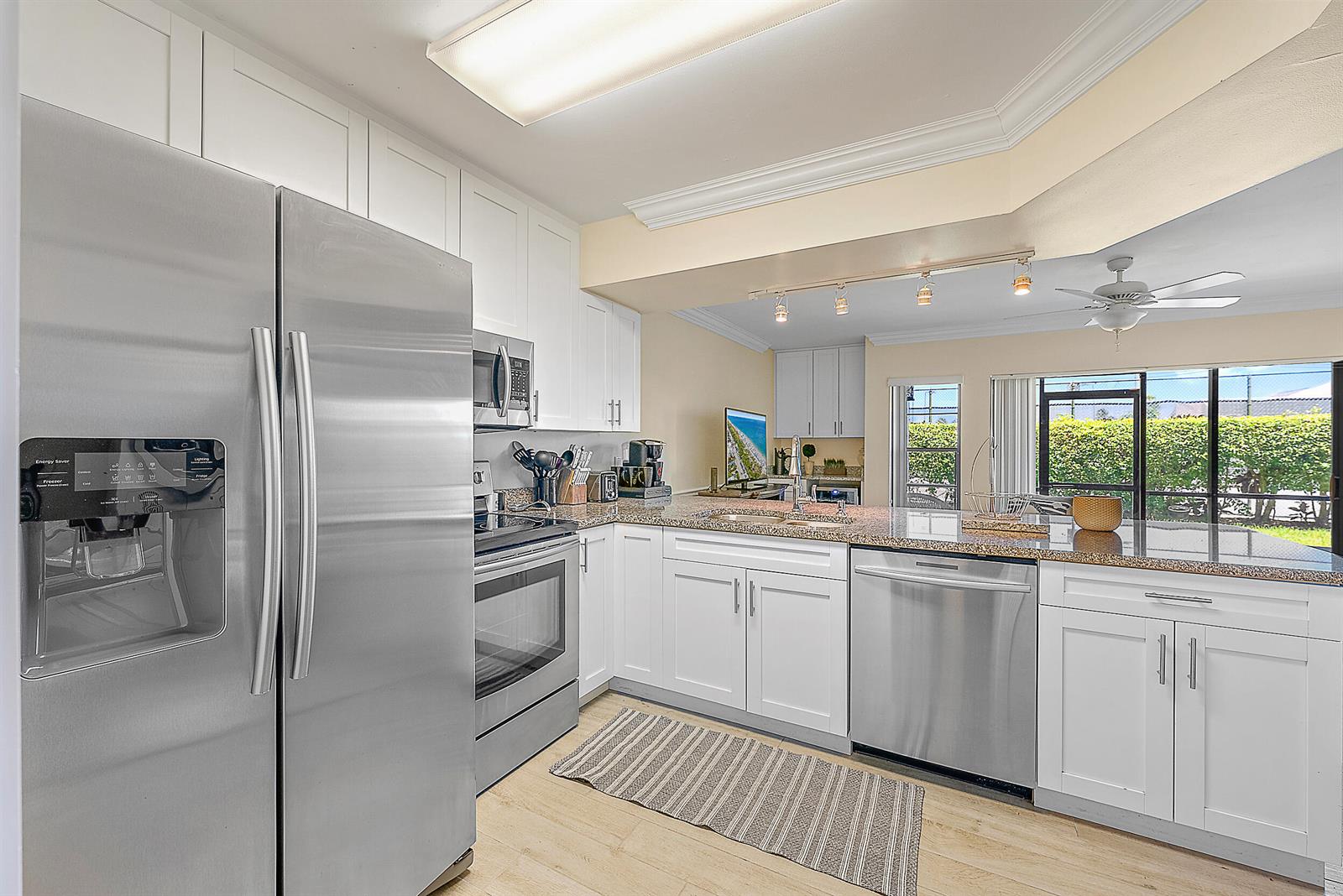 A kitchen with white cabinets, stainless steel appliances, granite countertops, and a view of greenery — 1605 S Us Highway 1, Jupiter FL 33477, JUPITER, FL