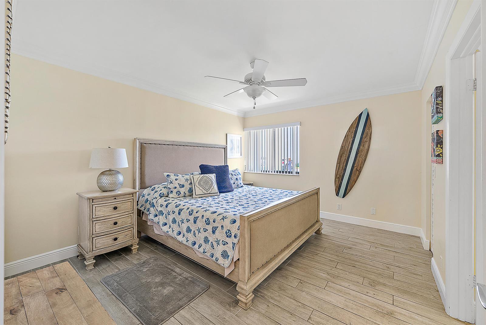 A bedroom features a bed with a seashell-patterned quilt, a surfboard wall decoration, and tile flooring — 1605 S Us Highway 1, Jupiter FL 33477, JUPITER, FL