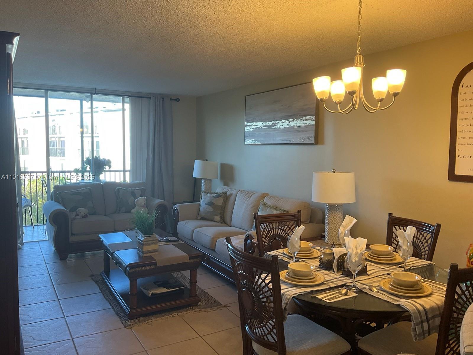 A living and dining area features tile floors, neutral furniture, and a glass-topped dining table — 8730 N Sherman Cir # 407, Miramar FL 33025, MIRAMAR, FL