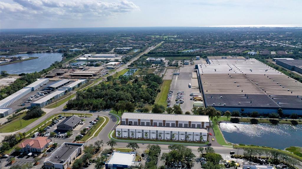 This aerial rendering shows a commercial building complex surrounded by parking lots, warehouses, and ponds — 5864 DEREK AVENUE UNIT 1-2, SARASOTA, FL