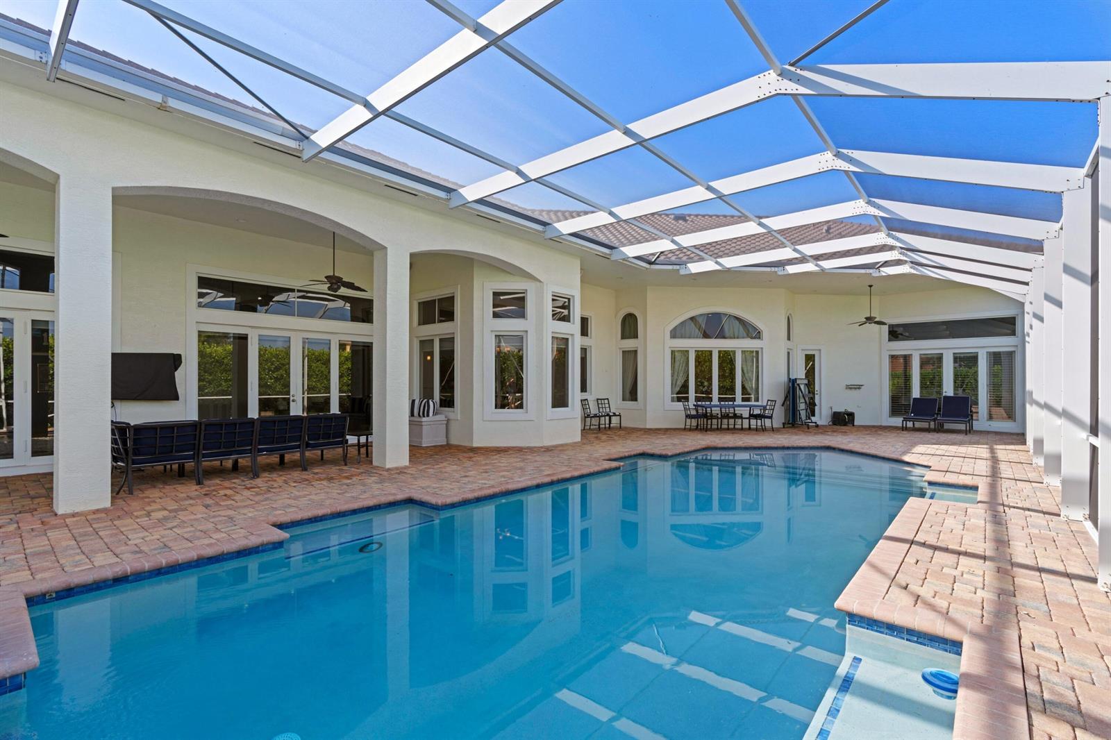 A screened-in patio features a swimming pool, brick pavers, and outdoor seating areas — 15885 Boeing Court, Wellington FL 33414, WELLINGTON, FL