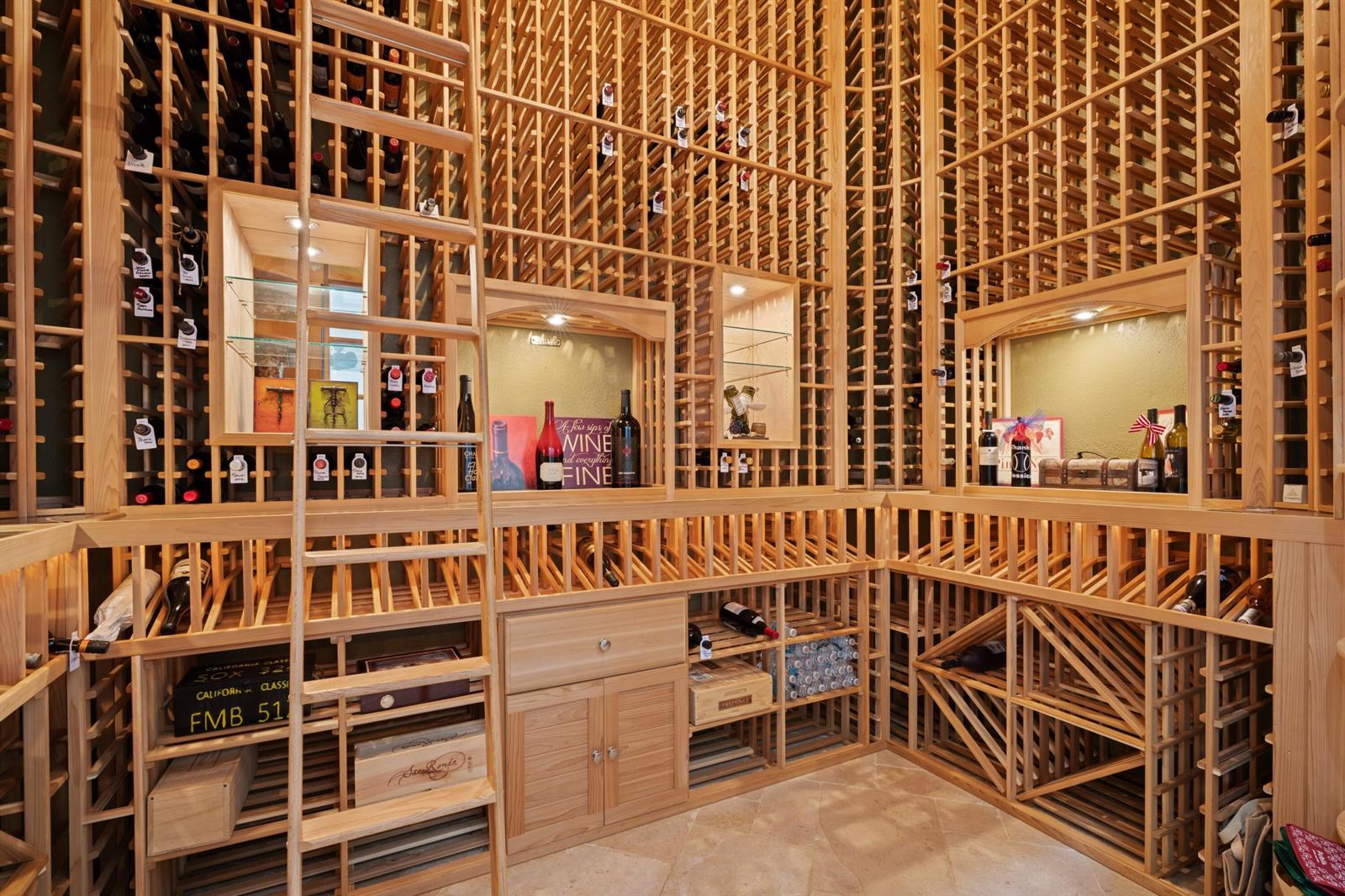 A custom wooden wine cellar featuring extensive grid shelving, a rolling ladder, and display niches — 15885 Boeing Court, Wellington FL 33414, WELLINGTON, FL