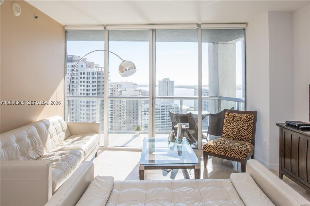 A living room features a white sofa, a glass coffee table, and floor-to-ceiling windows — 475 Brickell ave # 2707, Miami FL 33131, MIAMI, FL